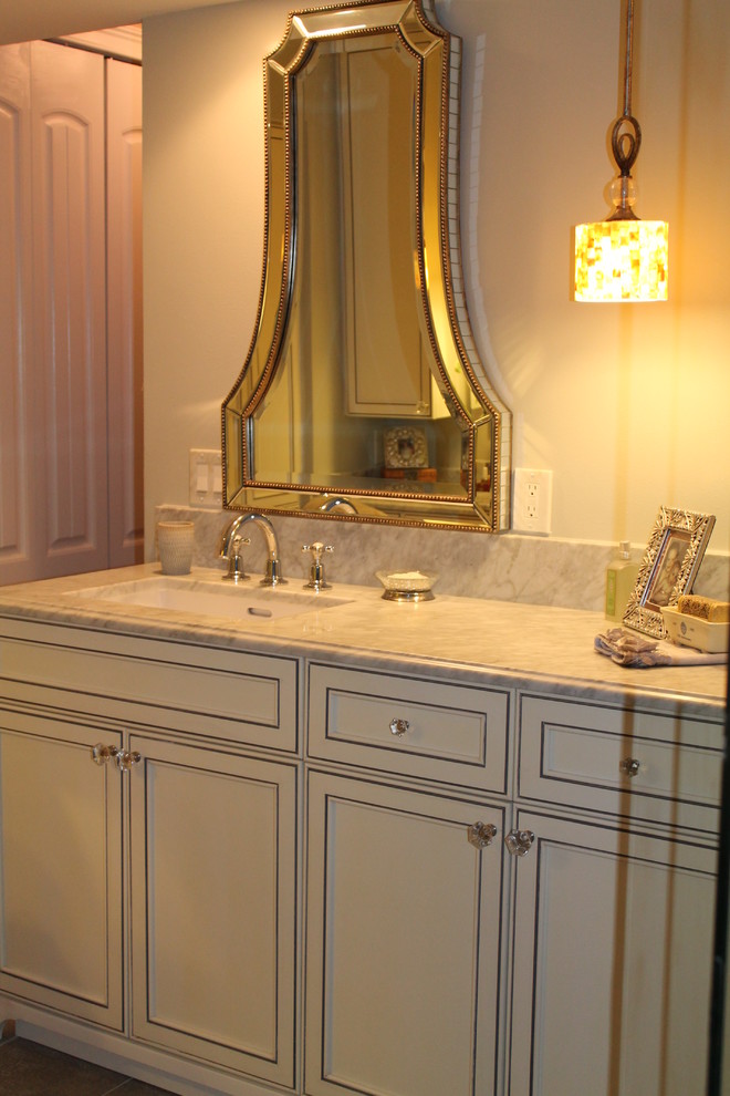 Cette image montre une salle de bain traditionnelle avec un placard à porte affleurante, des portes de placard blanches et un plan de toilette en marbre.