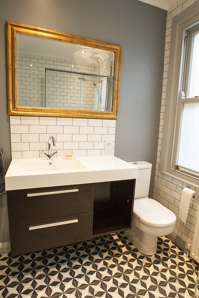 Eklektisk inredning av ett litet badrum, med ett konsol handfat, en hörndusch, en toalettstol med hel cisternkåpa, flerfärgad kakel, grå väggar, klinkergolv i keramik och stenkakel