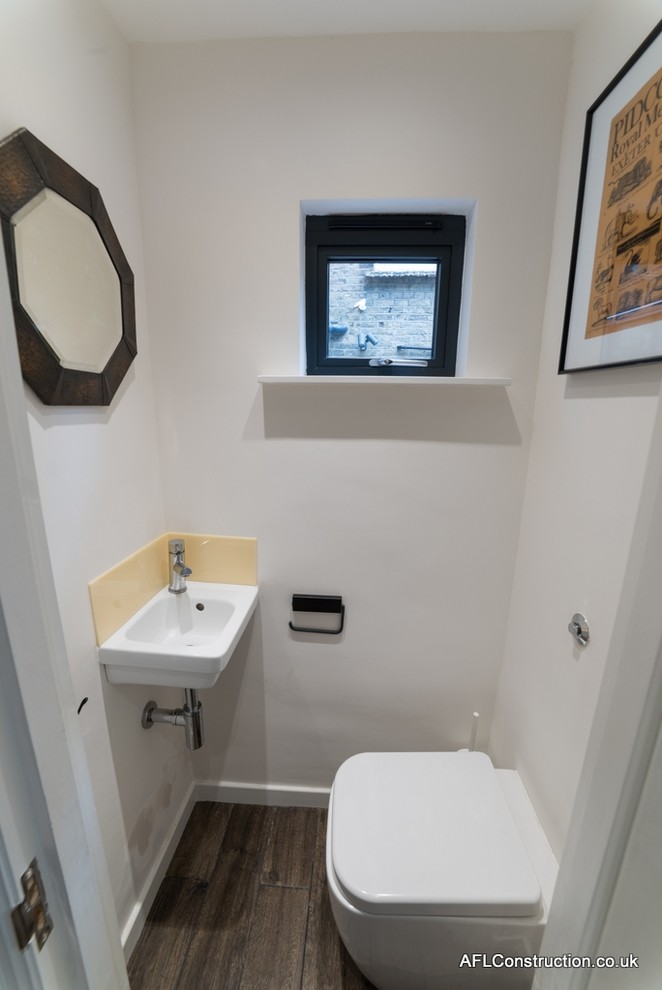 This is an example of a small contemporary cloakroom in London with a wall mounted toilet, brown tiles, white walls and porcelain flooring.