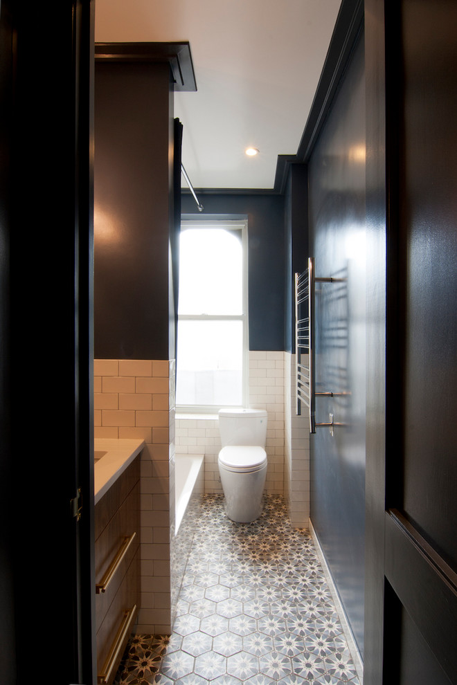 Пример оригинального дизайна: маленькая ванная комната в стиле неоклассика (современная классика) с плоскими фасадами, фасадами цвета дерева среднего тона, ванной в нише, душем над ванной, унитазом-моноблоком, белой плиткой, керамической плиткой, синими стенами, полом из терракотовой плитки, врезной раковиной, столешницей из искусственного кварца, синим полом, шторкой для ванной и белой столешницей для на участке и в саду