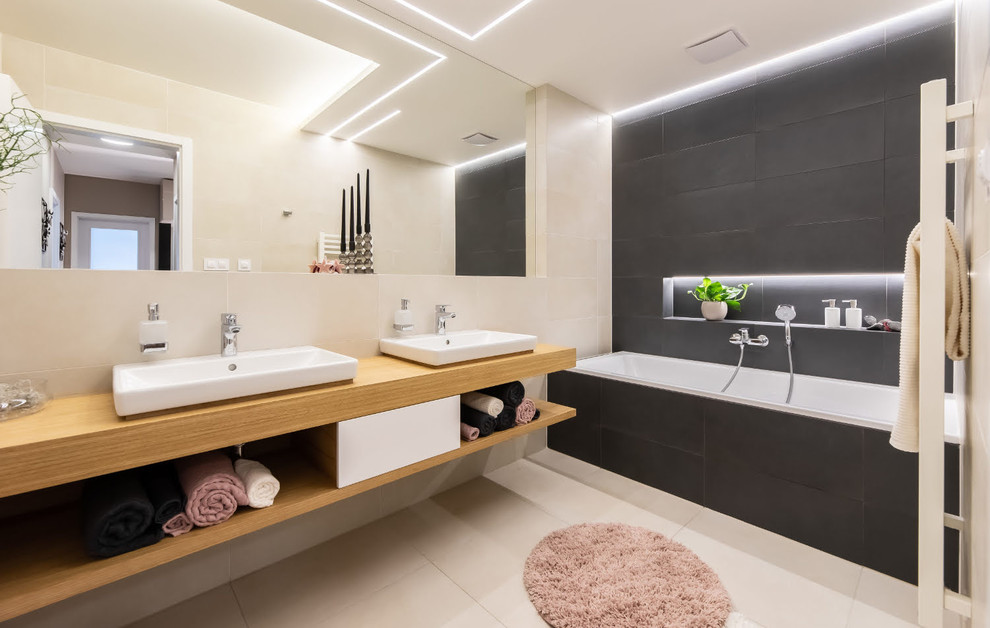 Идея дизайна: маленькая главная ванная комната в современном стиле с плоскими фасадами, ванной в нише, душем над ванной, полом из керамической плитки, накладной раковиной, столешницей из дерева и бежевым полом для на участке и в саду