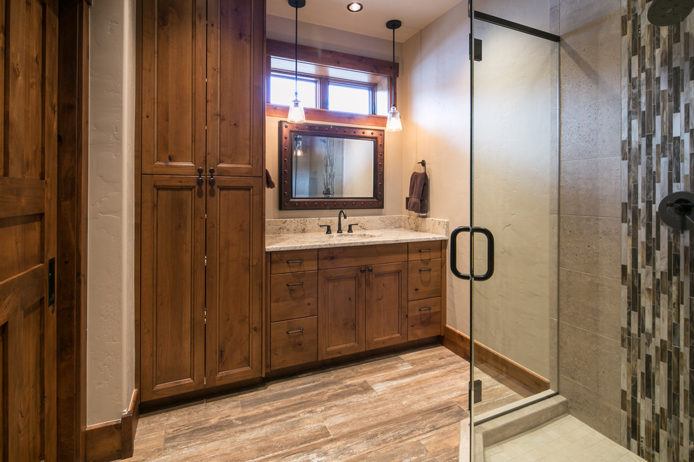 Cette photo montre une salle de bain principale montagne en bois brun de taille moyenne avec un placard avec porte à panneau encastré, une douche d'angle, un mur beige, un sol en bois brun et un lavabo encastré.