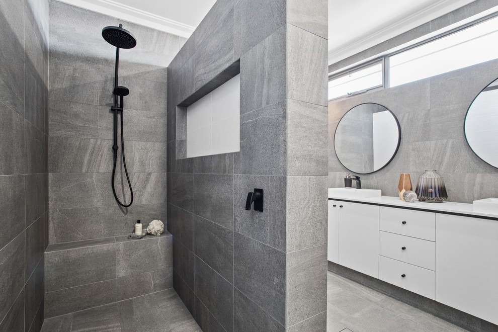 Modelo de cuarto de baño contemporáneo con armarios con paneles lisos, puertas de armario blancas, ducha abierta, baldosas y/o azulejos grises, aseo y ducha, lavabo sobreencimera, suelo gris y ducha abierta