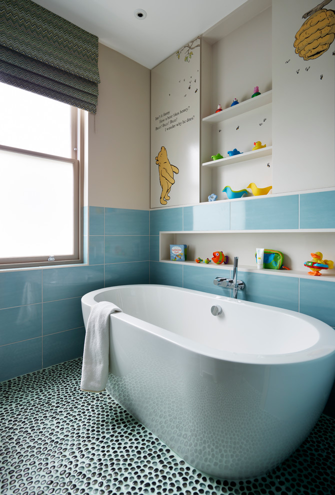 Foto på ett funkis badrum för barn, med ett fristående badkar, keramikplattor, beige väggar och klinkergolv i småsten