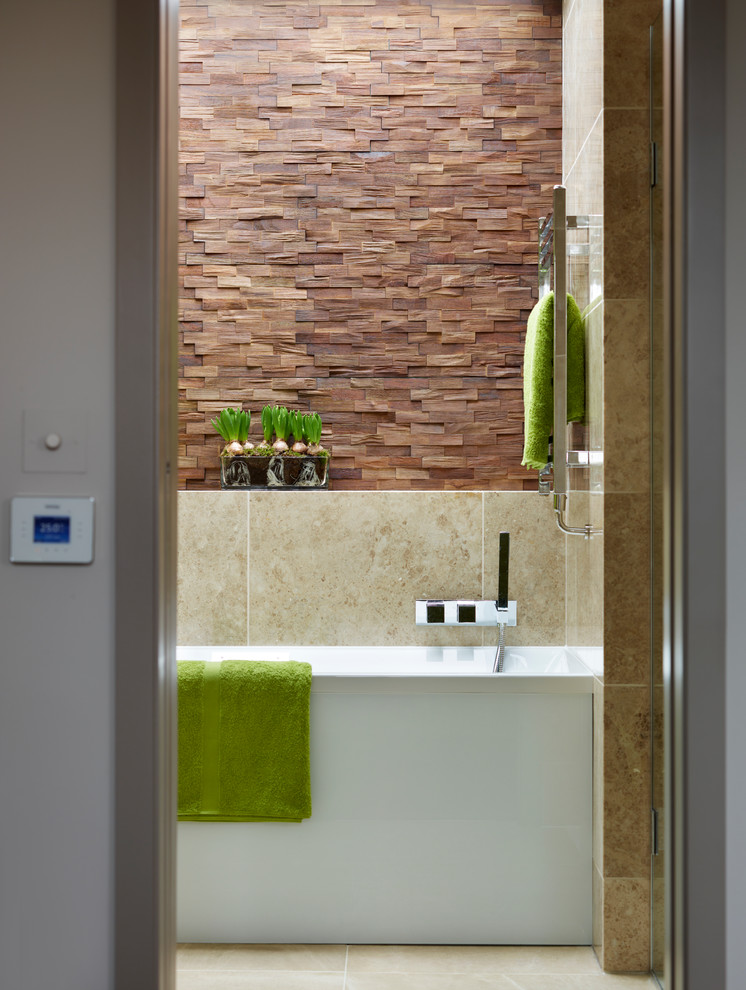 ロンドンにあるコンテンポラリースタイルのおしゃれなマスターバスルーム (壁付け型シンク、ドロップイン型浴槽、オープン型シャワー、壁掛け式トイレ、茶色いタイル、石タイル、トラバーチンの床) の写真