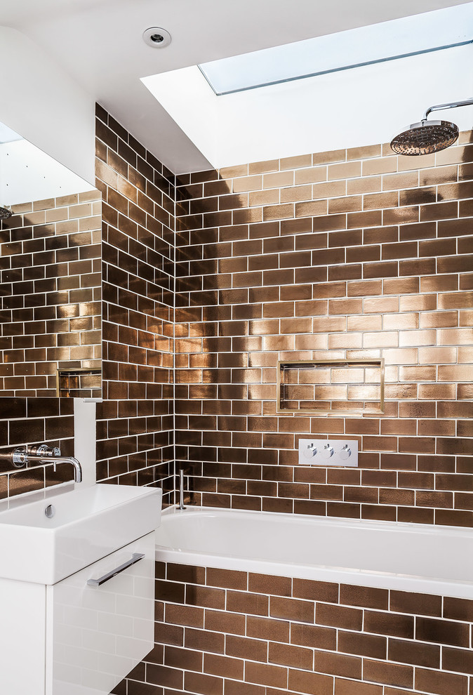 Example of a trendy brown tile and subway tile bathroom design in London with flat-panel cabinets, white cabinets and a console sink