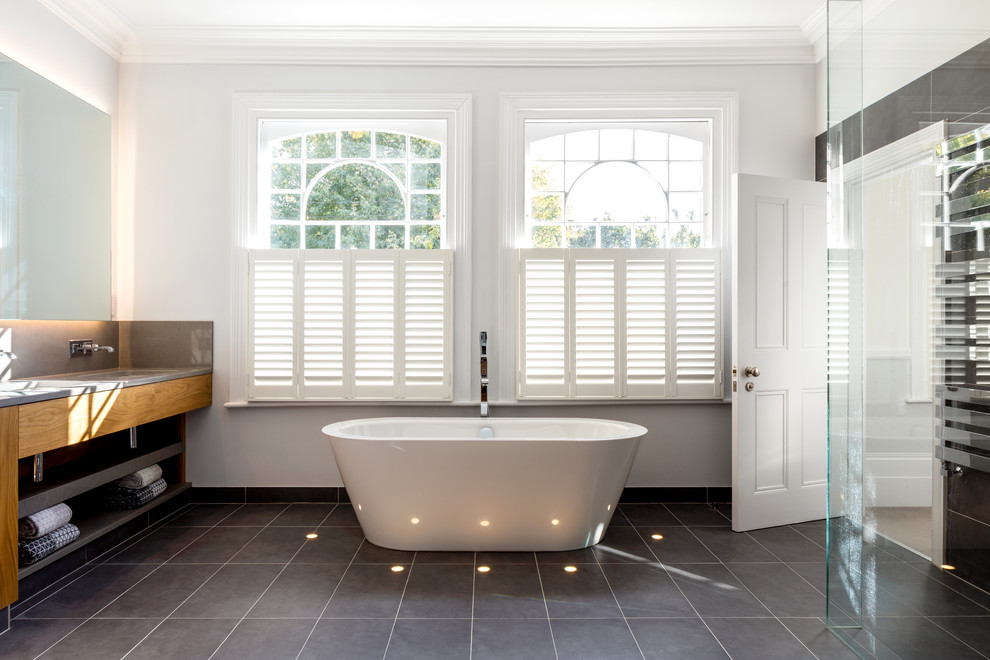 Design ideas for a large contemporary ensuite bathroom in London with flat-panel cabinets, medium wood cabinets, a freestanding bath, a walk-in shower, black tiles, porcelain tiles, white walls, porcelain flooring, a built-in sink, engineered stone worktops, black floors and an open shower.