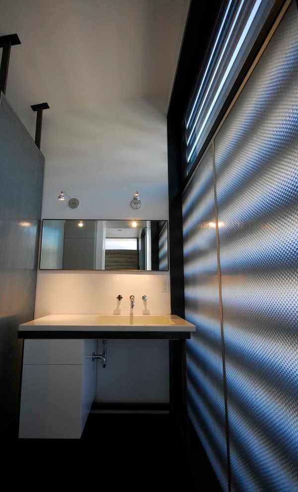 Inspiration for a small modern shower room bathroom in Other with flat-panel cabinets, white cabinets, grey walls, concrete flooring, a built-in sink and solid surface worktops.