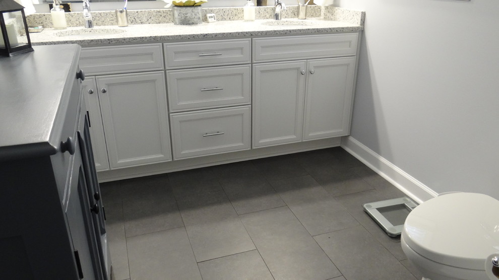 Cette image montre une petite salle de bain principale design avec un placard à porte shaker, des portes de placard blanches, un carrelage gris, des carreaux de porcelaine, un mur gris, un sol en carrelage de porcelaine, un lavabo encastré et un plan de toilette en quartz modifié.