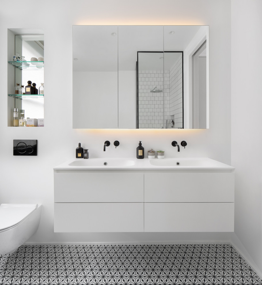 Skandinavisches Badezimmer mit flächenbündigen Schrankfronten, weißen Schränken, weißer Wandfarbe, integriertem Waschbecken, buntem Boden, weißer Waschtischplatte und Doppelwaschbecken in London