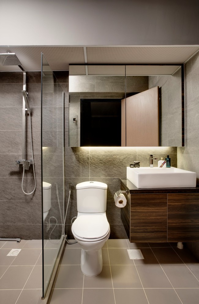 Idéer för industriella badrum med dusch, med släta luckor, skåp i mörkt trä, en hörndusch, en toalettstol med separat cisternkåpa, grå kakel, ett fristående handfat och beiget golv