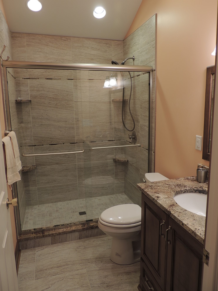 Inredning av ett klassiskt litet en-suite badrum, med ett undermonterad handfat, luckor med upphöjd panel, skåp i mörkt trä, granitbänkskiva, en dusch i en alkov, en toalettstol med hel cisternkåpa, beige kakel, porslinskakel och rosa väggar