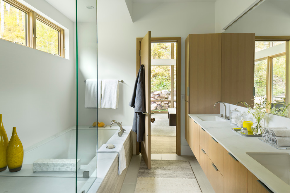 Imagen de cuarto de baño principal contemporáneo con armarios con paneles lisos, puertas de armario de madera clara, bañera encastrada sin remate, paredes blancas y lavabo bajoencimera