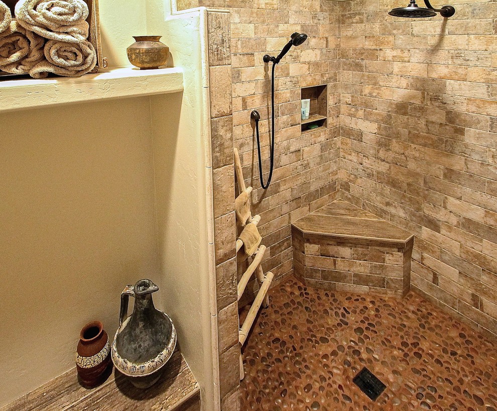 Modelo de cuarto de baño principal rústico de tamaño medio con ducha a ras de suelo, baldosas y/o azulejos de piedra, paredes beige y suelo de baldosas tipo guijarro