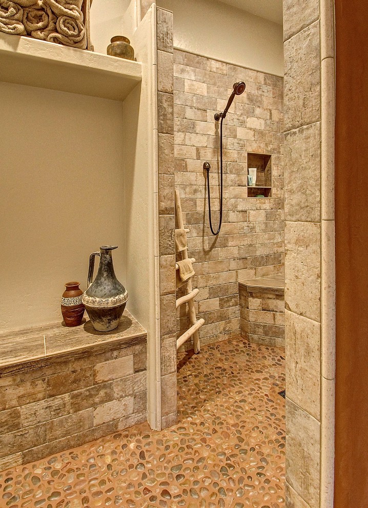 Example of a mid-sized mountain style master stone tile pebble tile floor walk-in shower design in Phoenix with beige walls