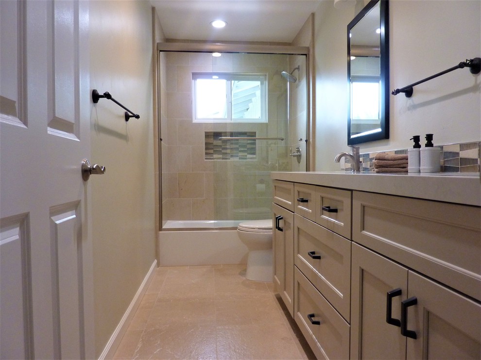 На фото: ванная комната среднего размера в стиле неоклассика (современная классика) с фасадами в стиле шейкер, бежевыми фасадами, ванной в нише, душем над ванной, коричневой плиткой, плиткой из известняка, полом из известняка, врезной раковиной, столешницей из искусственного кварца, коричневым полом, душем с раздвижными дверями и белой столешницей
