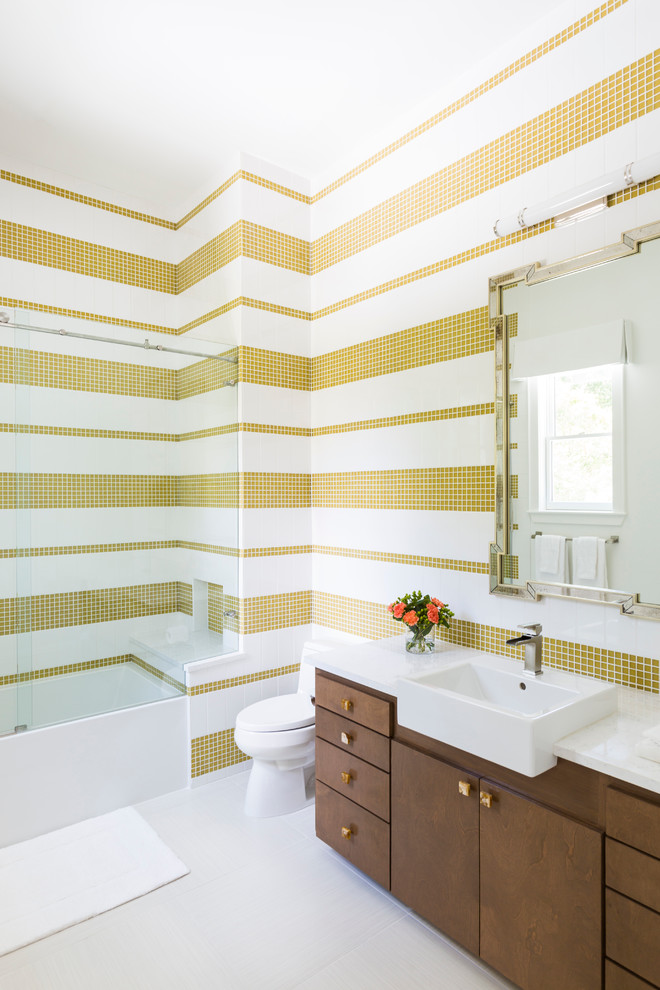 Inredning av ett modernt badrum, med släta luckor, skåp i mörkt trä, en dusch i en alkov, vit kakel, gul kakel, mosaik, flerfärgade väggar, ett nedsänkt handfat och dusch med skjutdörr