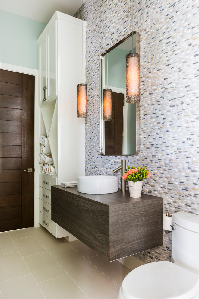 Modernes Duschbad mit verzierten Schränken, dunklen Holzschränken, Waschtisch aus Holz, farbigen Fliesen, Toilette mit Aufsatzspülkasten, Kieselfliesen, bunten Wänden, Aufsatzwaschbecken und Keramikboden in Houston