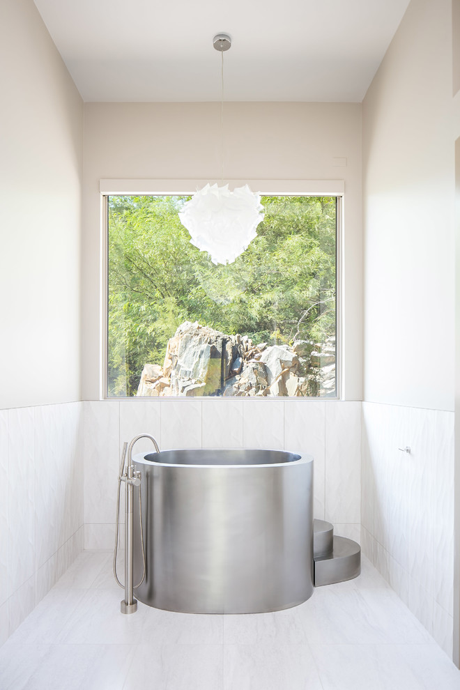 Aménagement d'une salle de bain contemporaine avec un bain japonais, un carrelage blanc, un mur gris et un sol blanc.