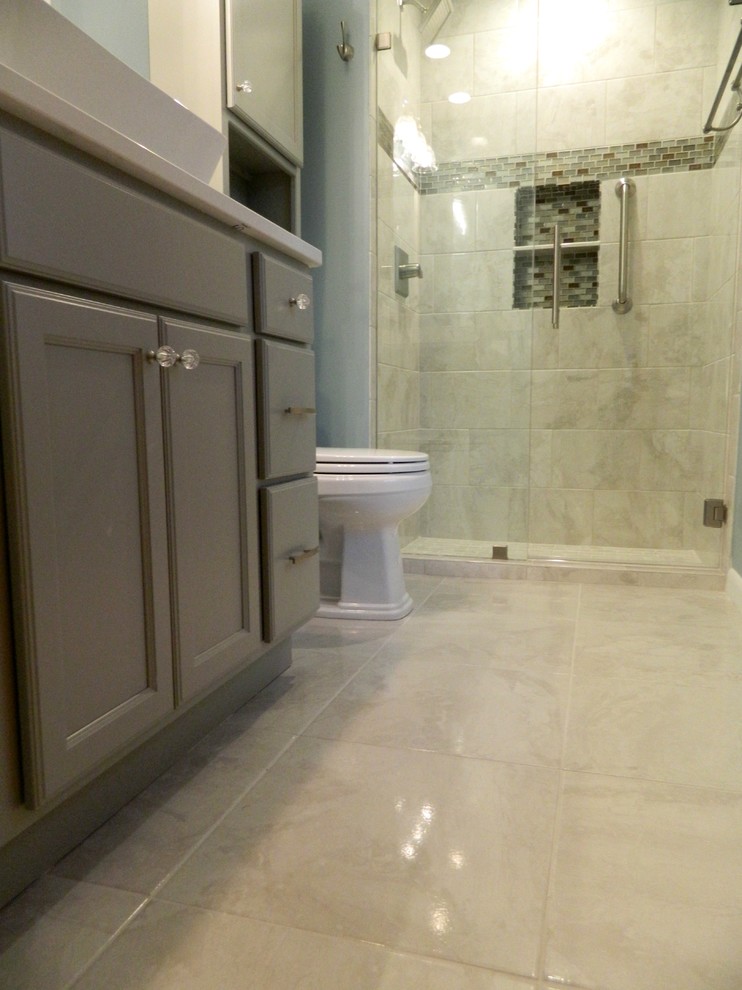 Exemple d'une salle de bain chic de taille moyenne avec un placard à porte shaker, des portes de placard grises, WC à poser, un carrelage gris, un carrelage de pierre, un mur bleu, un sol en carrelage de porcelaine, une vasque et un plan de toilette en quartz modifié.