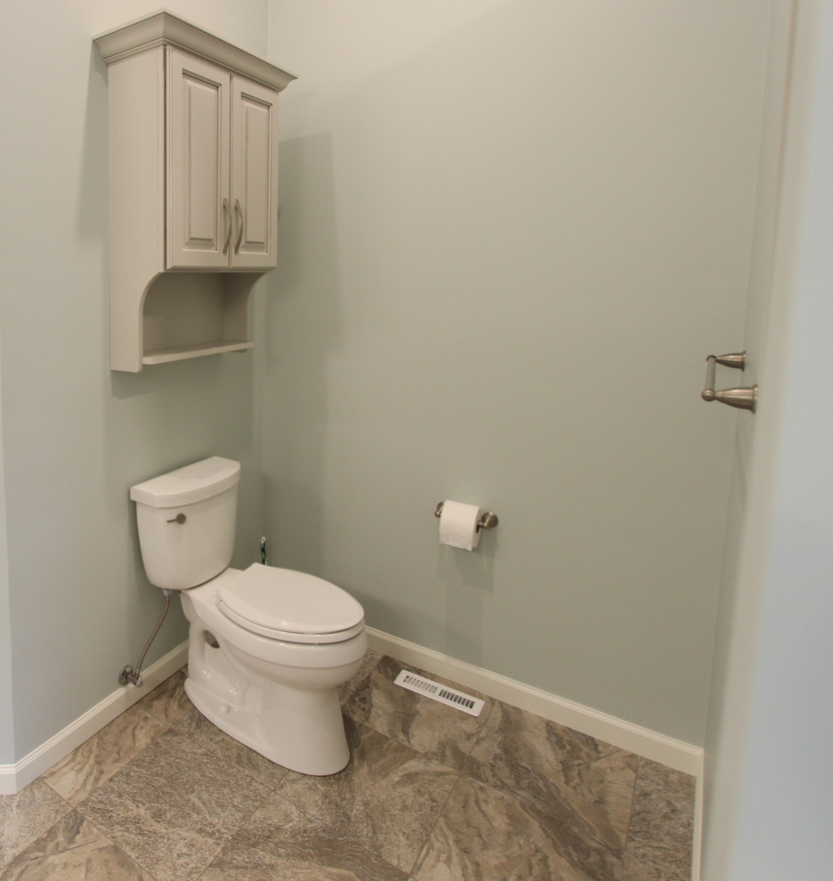 Klassisk inredning av ett mellanstort beige beige toalett, med luckor med upphöjd panel, grå skåp, en toalettstol med separat cisternkåpa, cementgolv, ett undermonterad handfat, bänkskiva i kvarts och beiget golv