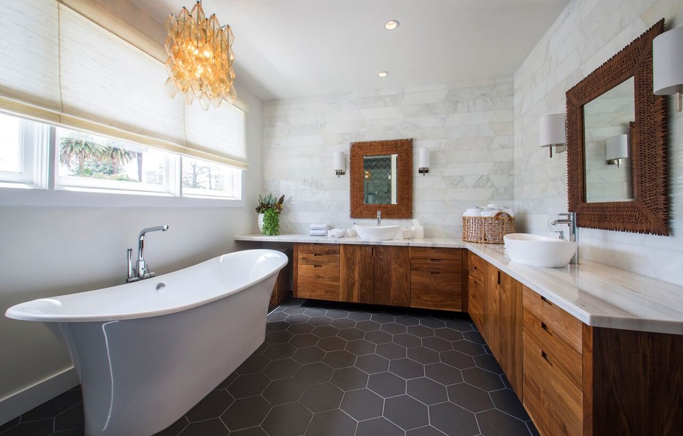 Exemple d'une salle de bain principale tendance en bois brun avec un placard à porte plane, une baignoire indépendante, un mur blanc et une vasque.