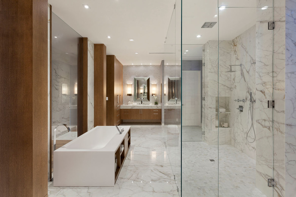 На фото: огромная главная ванная комната в стиле модернизм с плоскими фасадами, фасадами цвета дерева среднего тона, отдельно стоящей ванной, двойным душем, белой плиткой, мраморным полом и мраморной столешницей
