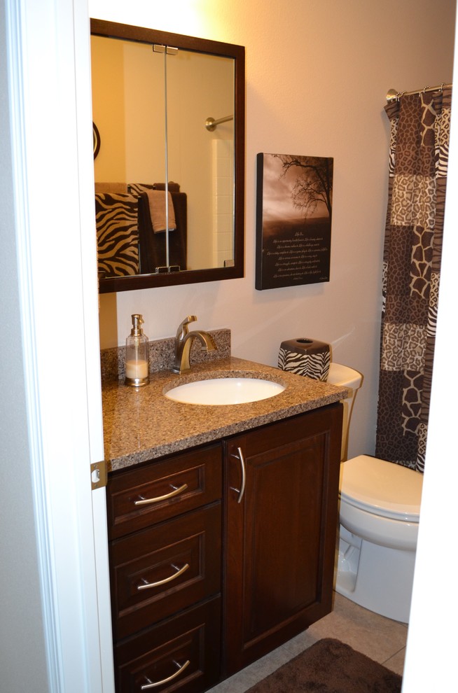 Immagine di una stanza da bagno tradizionale di medie dimensioni con lavabo sottopiano, ante con bugna sagomata, ante in legno bruno e top in quarzo composito