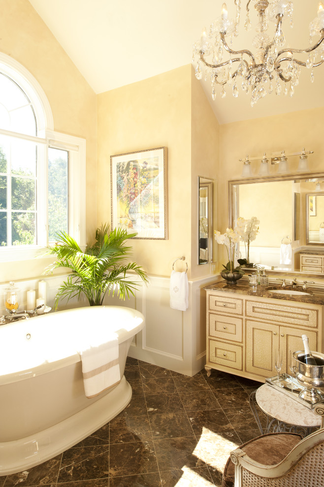 Пример оригинального дизайна: ванная комната в классическом стиле с отдельно стоящей ванной и желтыми стенами