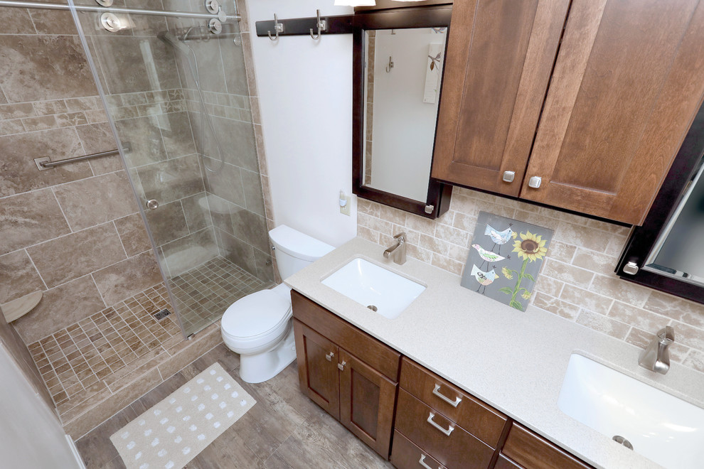Inspiration for a small classic ensuite bathroom in Other with shaker cabinets, medium wood cabinets, a two-piece toilet, beige walls, laminate floors, a submerged sink, brown floors and a sliding door.