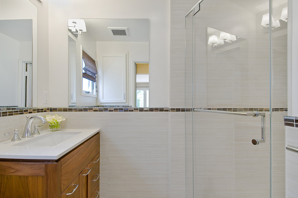 Immagine di una stanza da bagno contemporanea con lavabo sottopiano, ante in stile shaker, ante in legno scuro, doccia alcova e piastrelle beige
