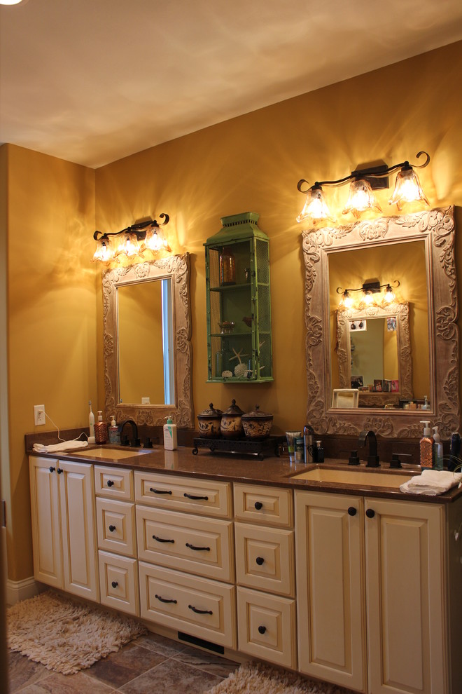 На фото: главная ванная комната среднего размера в стиле кантри с монолитной раковиной, фасадами с выступающей филенкой, бежевыми фасадами, столешницей из оникса и желтыми стенами с