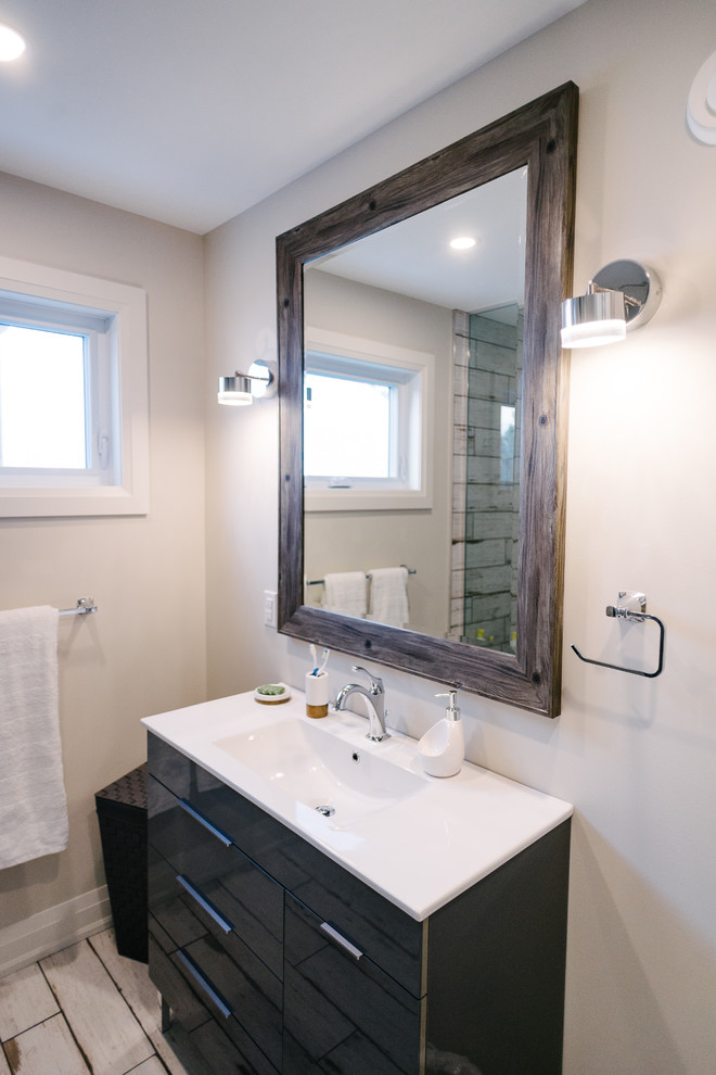 Medium sized beach style shower room bathroom with shaker cabinets, black cabinets, an alcove shower, a one-piece toilet, multi-coloured tiles, white walls, an integrated sink, white floors and a hinged door.