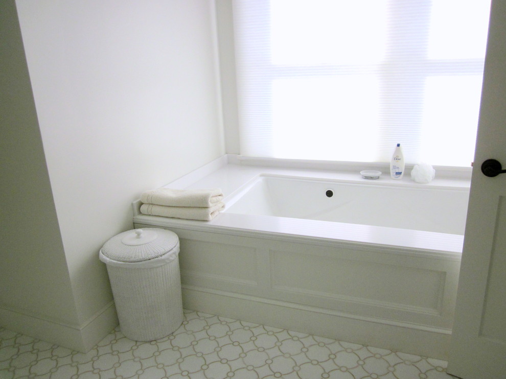 Inredning av ett klassiskt badrum, med marmorbänkskiva, ett undermonterat badkar, vit kakel och stenkakel