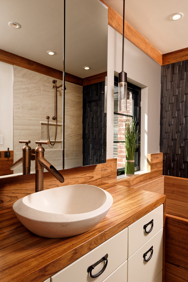 Asiatisk inredning av ett mellanstort en-suite badrum, med vita skåp, ett japanskt badkar, en toalettstol med hel cisternkåpa, klinkergolv i porslin, ett fristående handfat, träbänkskiva, släta luckor, en öppen dusch, svart kakel, stenkakel och beige väggar
