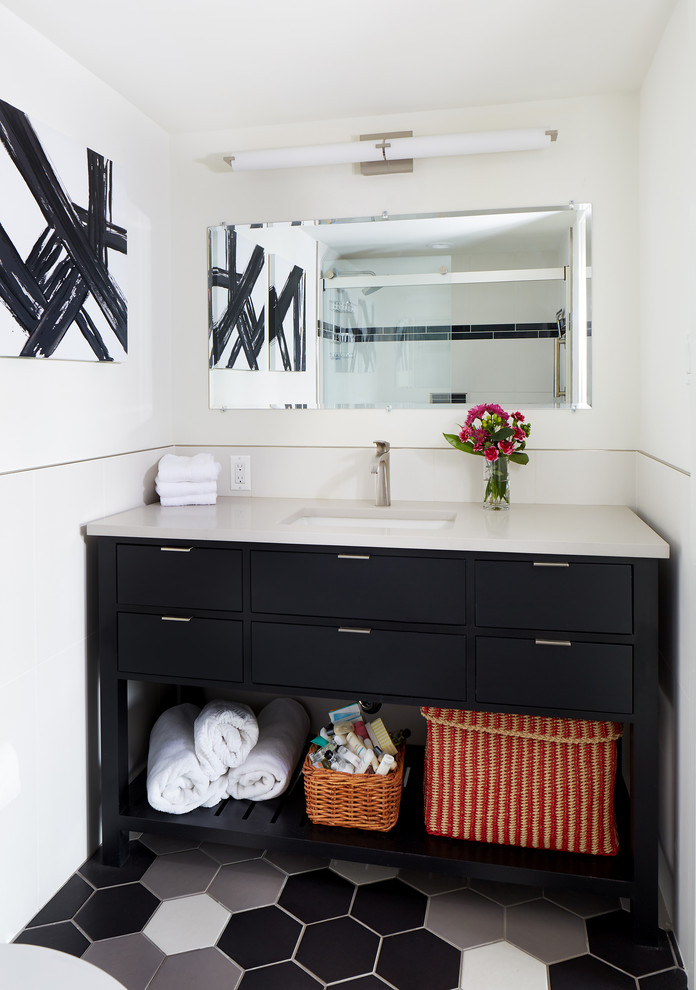 Modern inredning av ett badrum, med svarta skåp, vita väggar, ett undermonterad handfat och flerfärgat golv