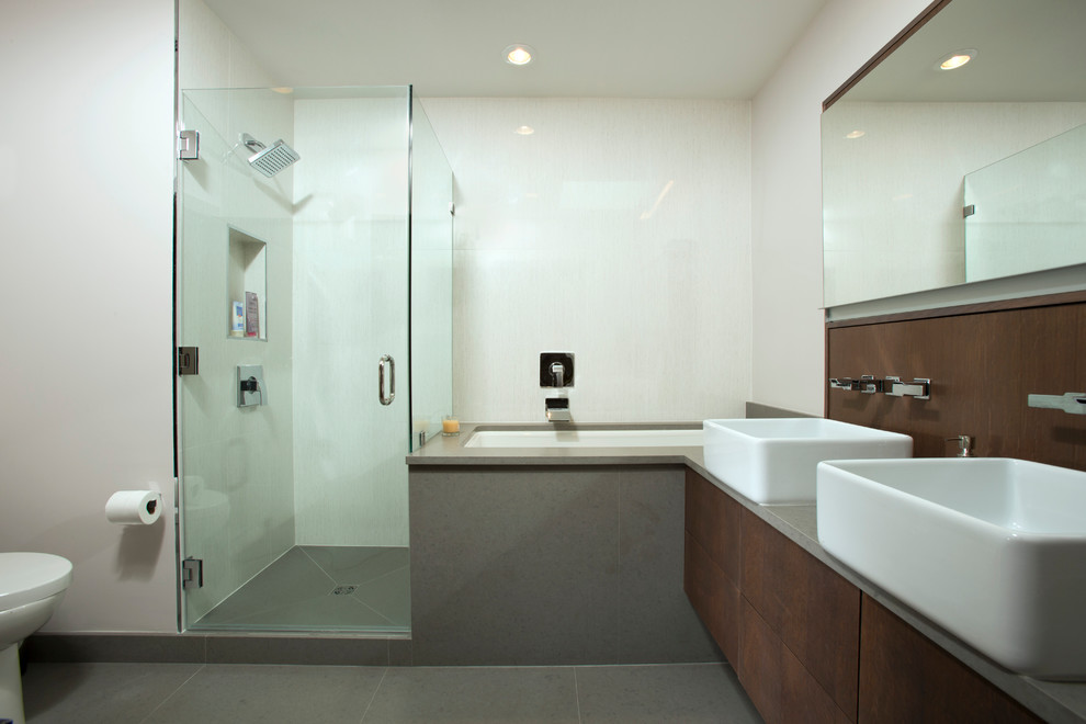 Large minimalist master gray tile and porcelain tile porcelain tile alcove shower photo in DC Metro with flat-panel cabinets, dark wood cabinets, an undermount tub, a one-piece toilet, white walls, a vessel sink and solid surface countertops