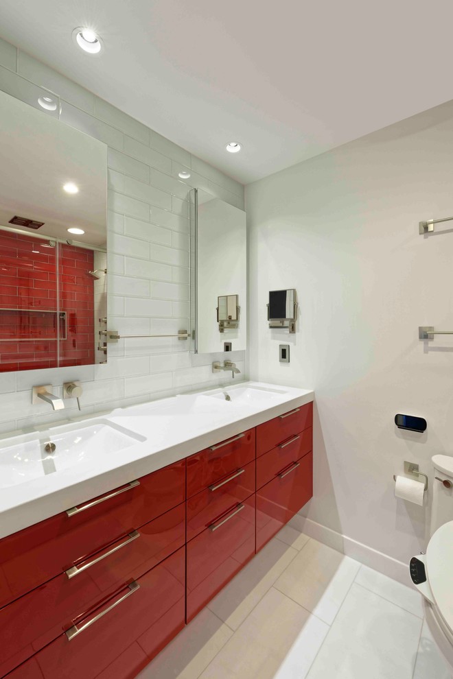 Idées déco pour une petite douche en alcôve moderne pour enfant avec un placard à porte plane, des portes de placard rouges, WC à poser, un carrelage rouge, un carrelage métro, un mur blanc, un sol en carrelage de porcelaine, un lavabo encastré et un plan de toilette en quartz modifié.