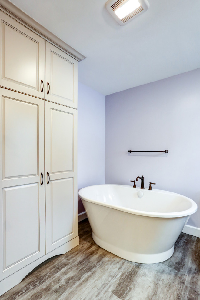 Idéer för att renovera ett mellanstort amerikanskt beige beige en-suite badrum, med beige skåp, ett fristående badkar, en dusch i en alkov, lila väggar, vinylgolv, ett undermonterad handfat, marmorbänkskiva, brunt golv och dusch med gångjärnsdörr