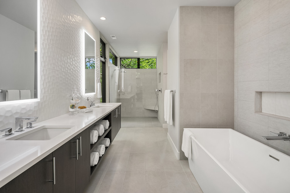Modernes Badezimmer mit flächenbündigen Schrankfronten, grauen Schränken, freistehender Badewanne, Duschnische, grauen Fliesen, grauer Wandfarbe, Unterbauwaschbecken, grauem Boden, Falttür-Duschabtrennung und weißer Waschtischplatte in Seattle