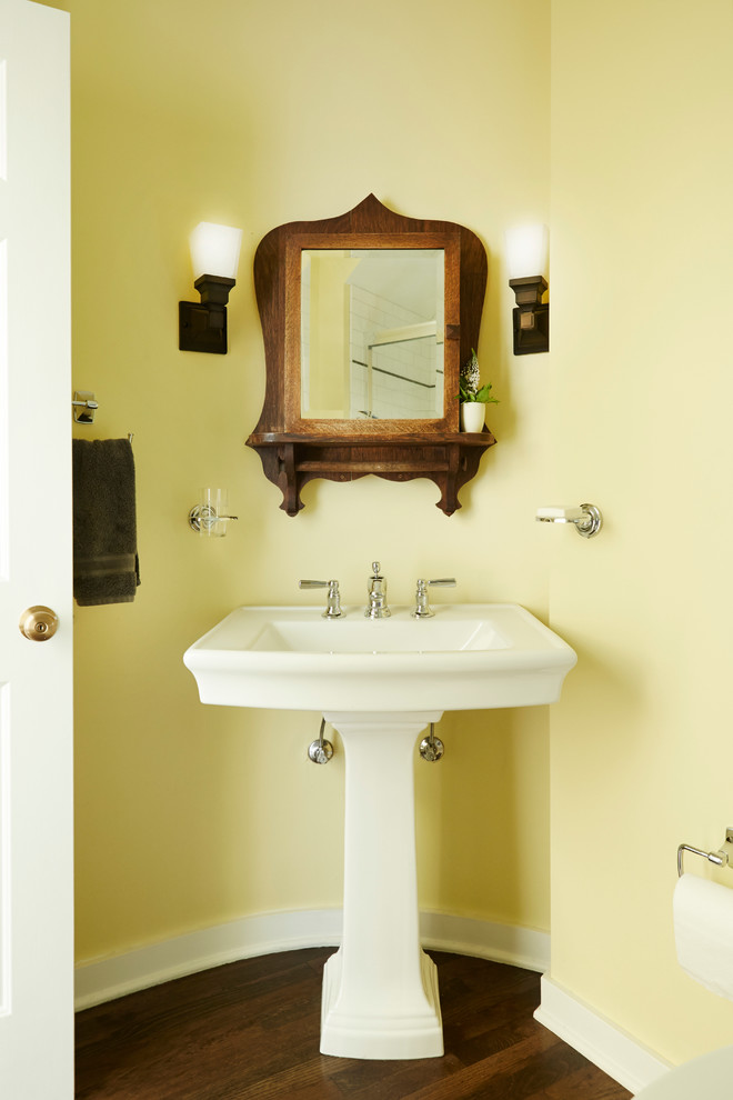 Пример оригинального дизайна: ванная комната среднего размера в классическом стиле с раковиной с пьедесталом, желтыми стенами и темным паркетным полом