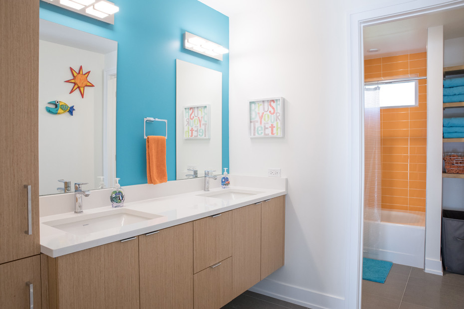 Стильный дизайн: большая детская ванная комната в современном стиле с плоскими фасадами, светлыми деревянными фасадами, ванной в нише, душем над ванной, унитазом-моноблоком, оранжевой плиткой, керамогранитной плиткой, синими стенами, полом из керамогранита, врезной раковиной, столешницей из искусственного кварца, серым полом и шторкой для ванной - последний тренд