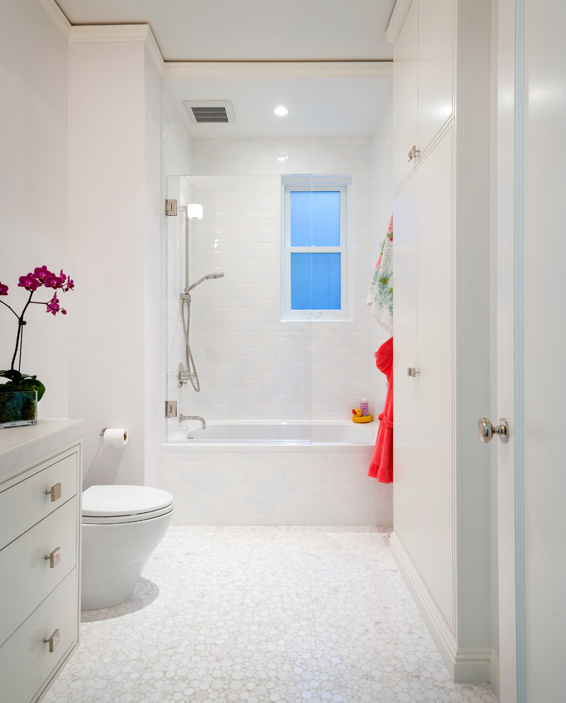 Cette photo montre une salle de bain tendance avec un placard à porte plane, des portes de placard blanches, une baignoire en alcôve, un combiné douche/baignoire, un carrelage blanc, un carrelage métro, un sol en carrelage de terre cuite et un sol blanc.
