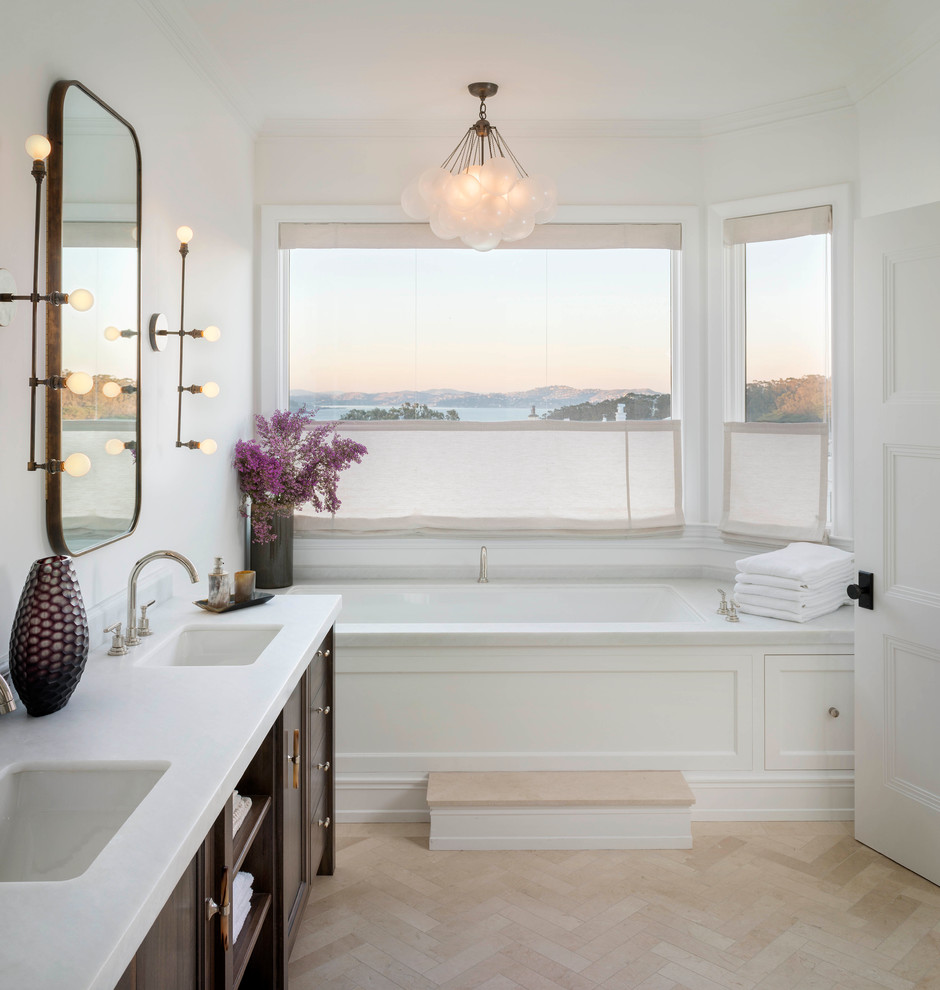 Réalisation d'une salle de bain tradition en bois foncé avec un lavabo encastré, une baignoire encastrée, un mur blanc et un sol beige.