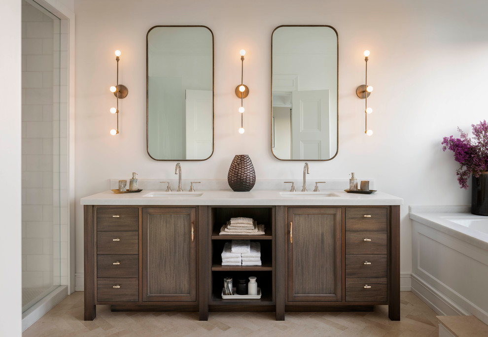 Inredning av ett klassiskt badrum, med ett undermonterad handfat, skåp i mörkt trä, ett undermonterat badkar, en dusch i en alkov, vit kakel, vita väggar och luckor med infälld panel