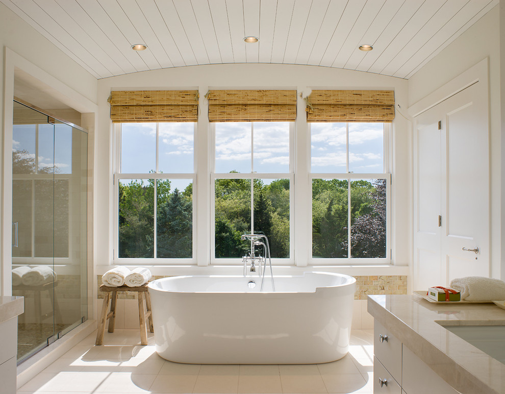 Immagine di una stanza da bagno country con lavabo sottopiano, ante lisce, ante bianche, vasca freestanding, piastrelle beige e pareti bianche