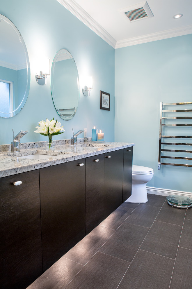 Foto de cuarto de baño principal clásico de tamaño medio con lavabo bajoencimera, armarios con paneles lisos, puertas de armario de madera en tonos medios, encimera de granito, bañera exenta, ducha esquinera, sanitario de dos piezas, baldosas y/o azulejos marrones, baldosas y/o azulejos de porcelana, paredes azules y suelo de baldosas de porcelana