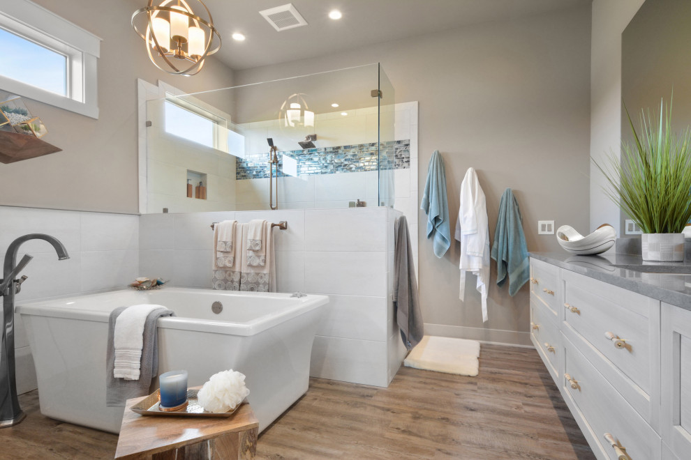 Foto på ett maritimt grå badrum, med skåp i shakerstil, grå skåp, ett fristående badkar, en hörndusch, grå väggar, mellanmörkt trägolv, ett undermonterad handfat och brunt golv