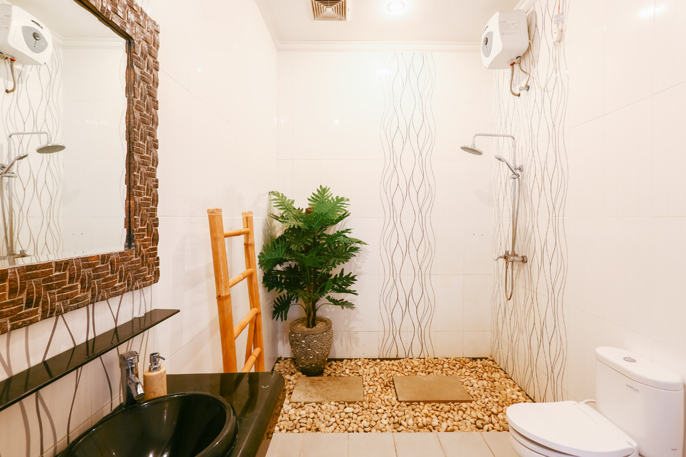 Duschbad mit offener Dusche, Wandtoilette mit Spülkasten, weißen Fliesen, weißer Wandfarbe, Einbauwaschbecken, beigem Boden, offener Dusche und schwarzer Waschtischplatte in Singapur