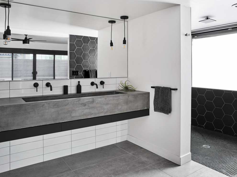 Modelo de cuarto de baño actual con ducha a ras de suelo, baldosas y/o azulejos negros, paredes blancas, lavabo de seno grande, suelo gris, ducha abierta y encimeras grises